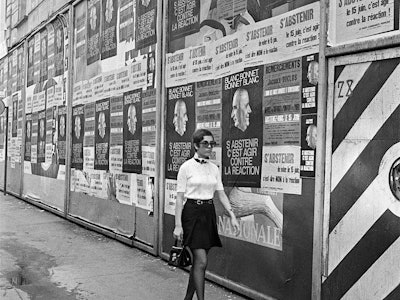 Une jeune femme passe devant les affiches du Parti Communiste appelant les Français à s'abstenir de ...