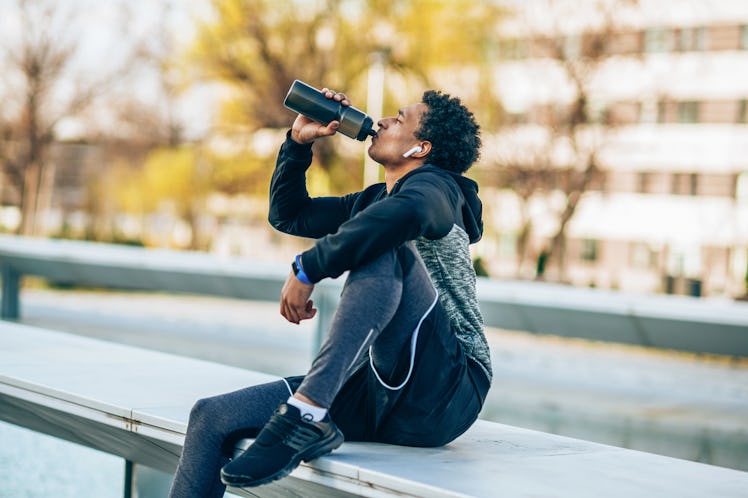 Young athlete drinking water after hard training