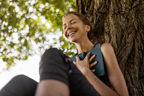 Happy young woman reading a book in public park