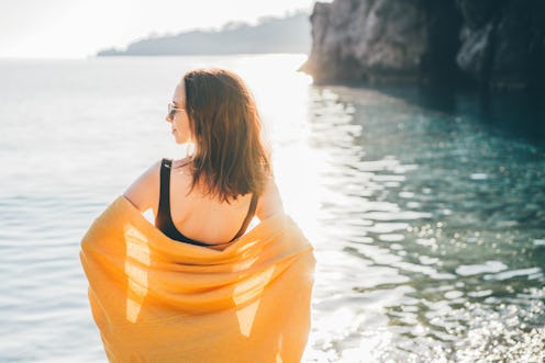 Woman relaxing at the beach holding swaying towel.