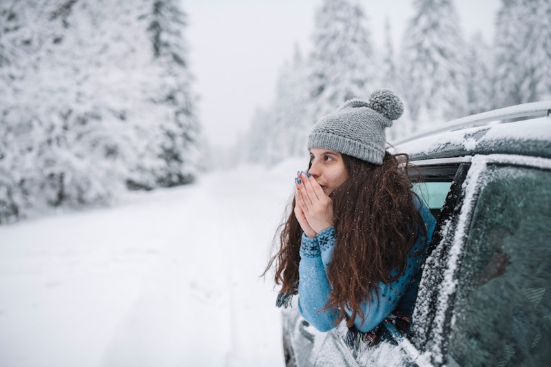 Woman warming hands on a winter road trip