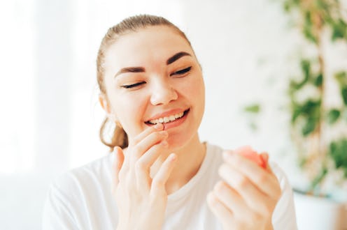 Girl lubricates lips with hygienic lipstick.
