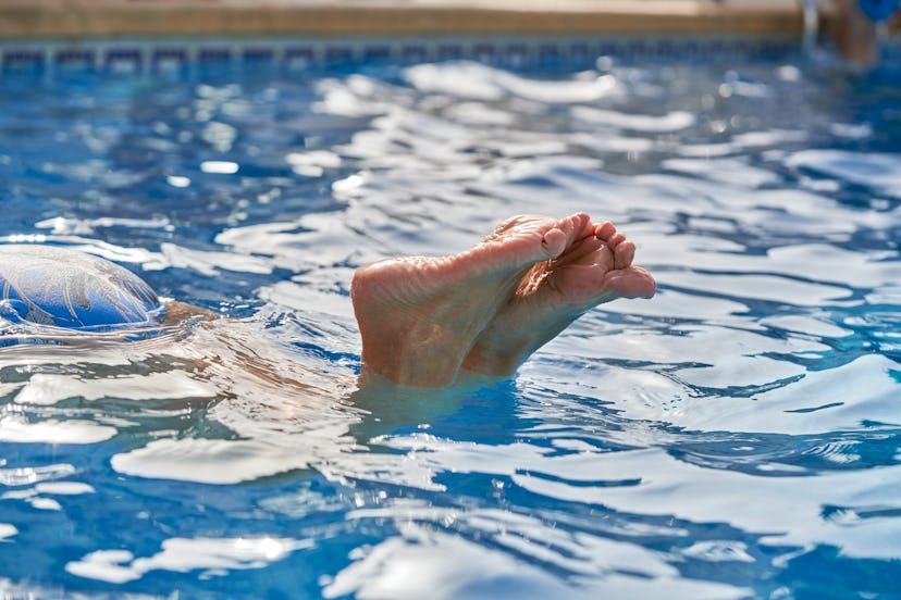 Wrinkled feet on water surface of unrecognizable person underwater diving