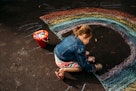 一个孩子用粉笔在柏油路上画了一道彩虹。