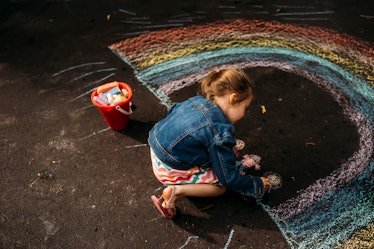 一个孩子用粉笔在柏油路上画了一道彩虹。