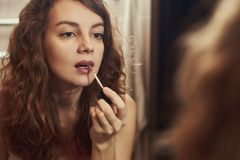 Woman putting on lipstick