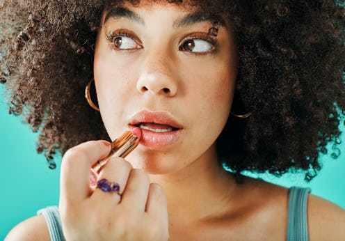 Afro model putting lipstick in the studio