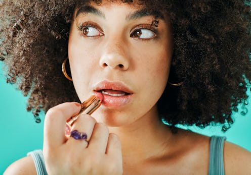 Afro model putting lipstick in the studio
