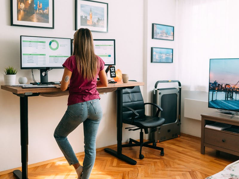 Rear view of woman working remotely from home at standing desk