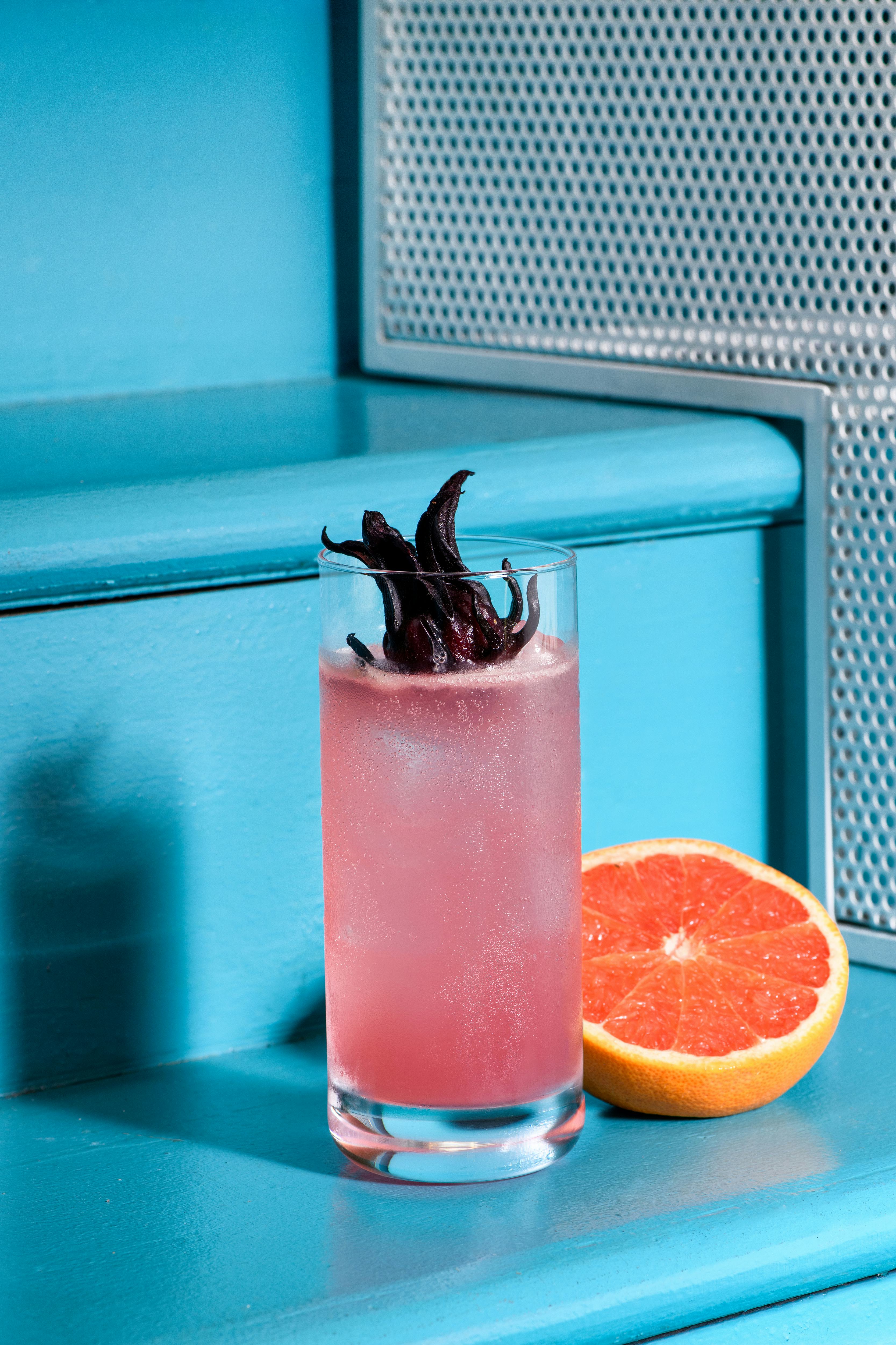 Pink paloma cocktail with grapefruits and roselle place on a blue stairs