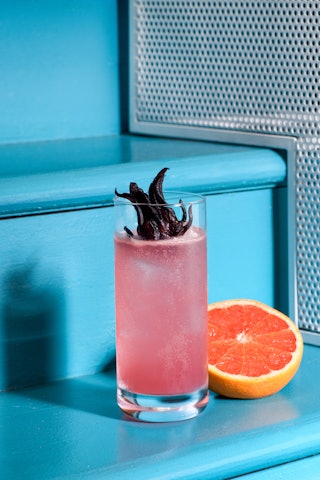 Pink paloma cocktail with grapefruits and roselle place on a blue stairs