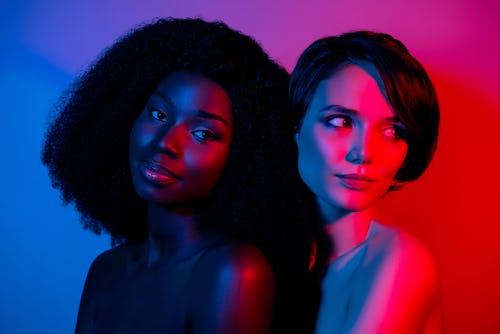 Two women holding each other in a room with colorful mood lighting. Mercury retrograde spring 2022 w...