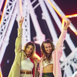 Female friends flash peace signs at a music festival. Festify, a spotify plug in, will turn your mus...