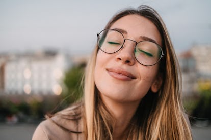 jovem sorri com os olhos fechados enquanto pensa sobre a astrologia de 23 de maio de 2022