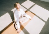 Beautiful authentic woman with short blond hair is meditating sitting in lotus position on yoga mat ...