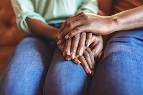 Closeup shot of an unrecognizable couple holding hands while sitting on sofa in the living room at h...