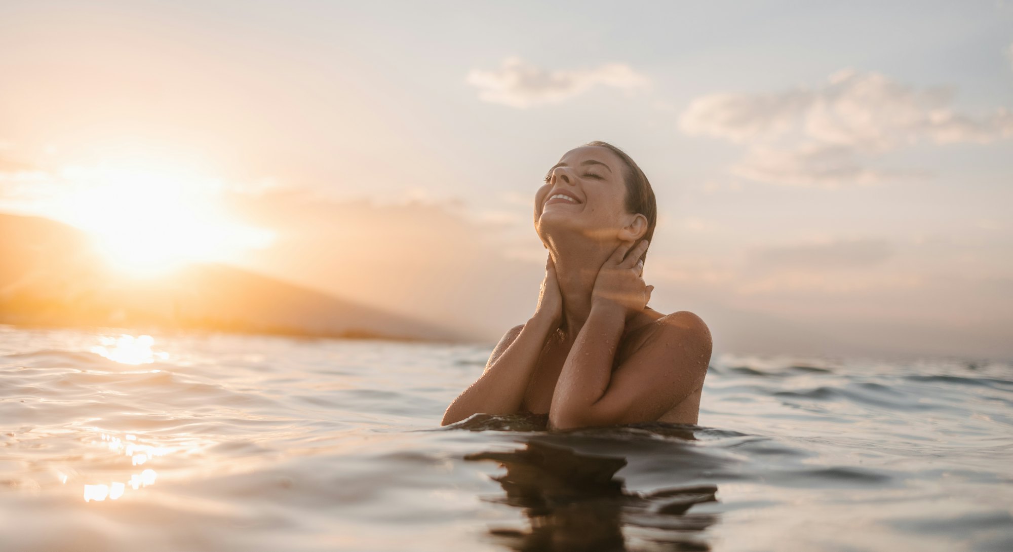 A young woman in sea water enjoying the sea and the sunset. Mercury Retrograde spring 2022 do's and ...