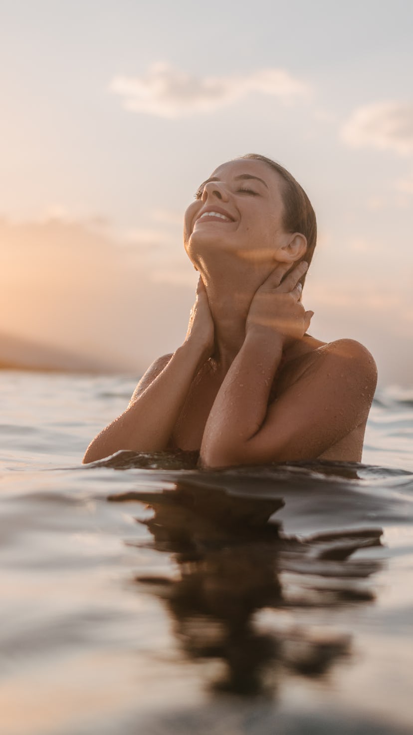 A young woman in sea water enjoying the sea and the sunset. Mercury Retrograde spring 2022 do's and ...