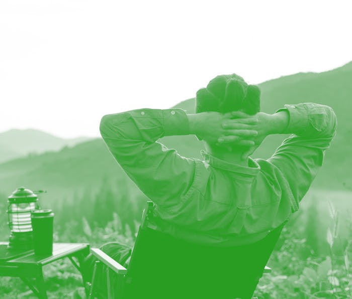 Rearview of Man sitting on camping chair enjoys summer camping on the mountain in morning.