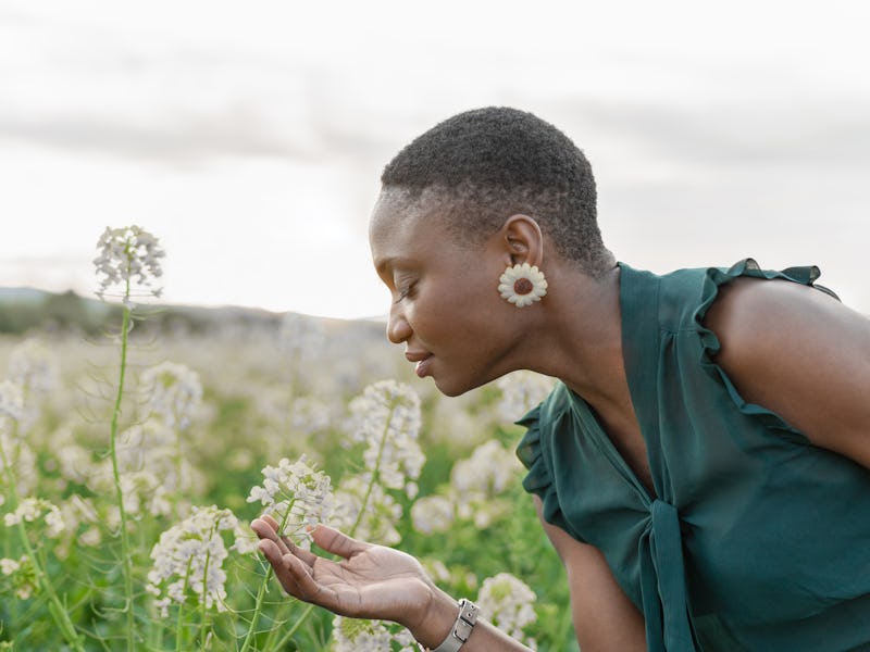 Portrait of beautiful woman smelling white flowers on field enjoying spring day outdoors