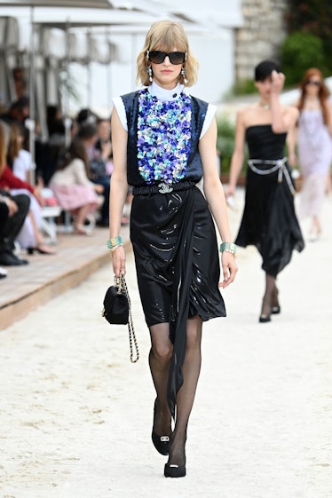 A model walking the runway during the Chanel Cruise 2023 Collection in a blue shirt and black skirt