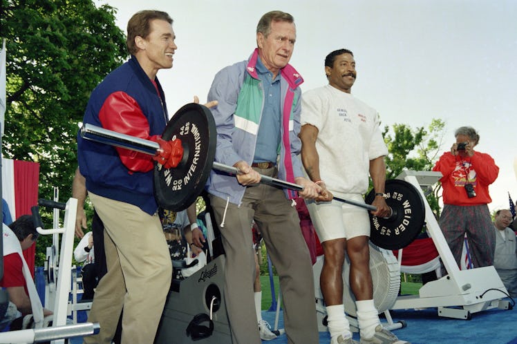 US President George Bush (C), assisted by movie star Arnold Schwarzenegger (L) and weightlifter Fair...