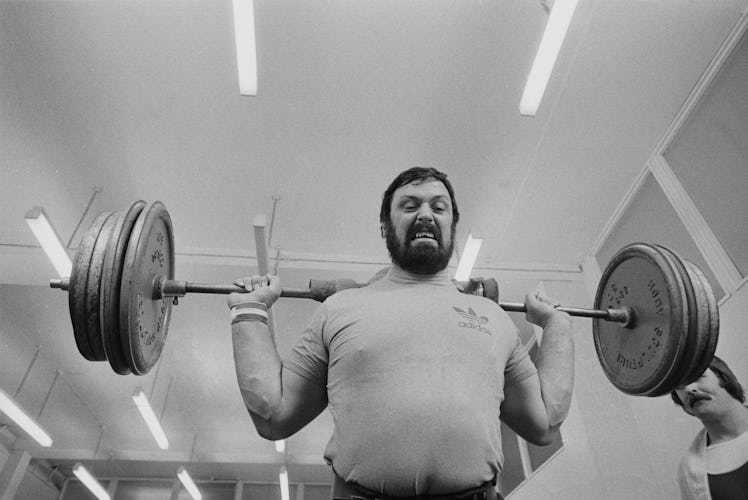 British strongman Geoff Capes showing the strain as he lifts a barbell, March 1976. (Photo by Evenin...