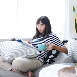 Young woman sitting on sofa reading magazine and drink coffee leisure activity in weekend