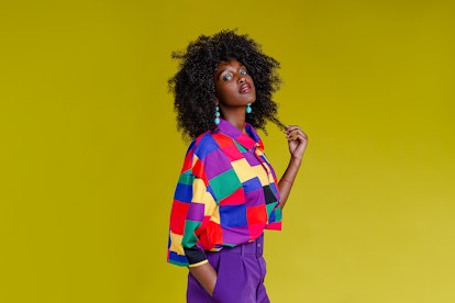 A portrait of a fashionable woman in colorful retro style shirt in front of yellow background