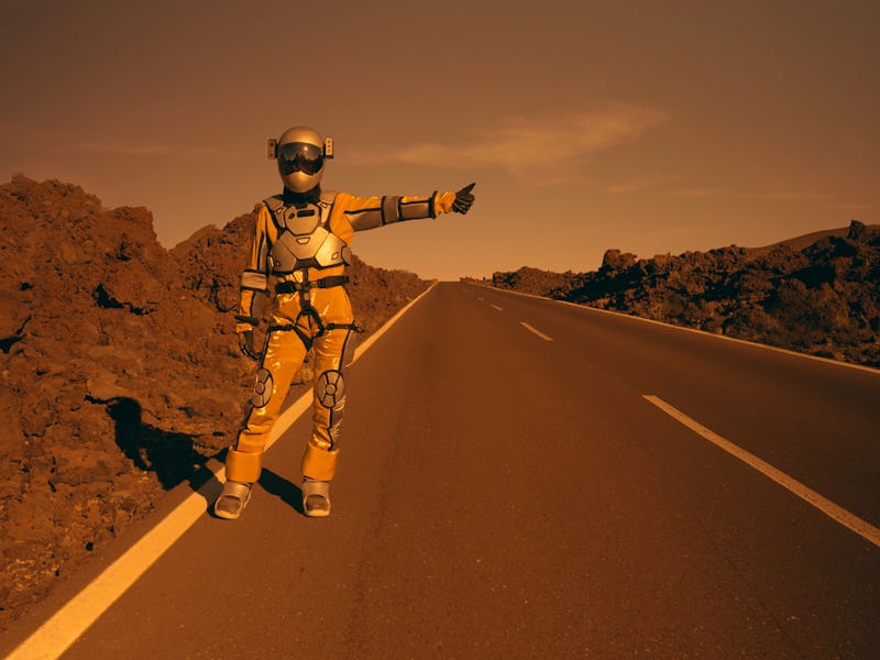 Astronaut in professional space suit holding sign with destination name. Catching a lift. Surreal sc...