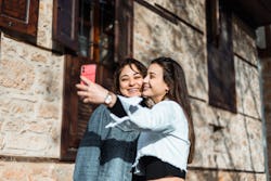 Two young woman taking selfie together on the street. Here's how to use Twitter Circle, a new close ...