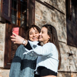 Two young woman taking selfie together on the street. Here's how to use Twitter Circle, a new close ...
