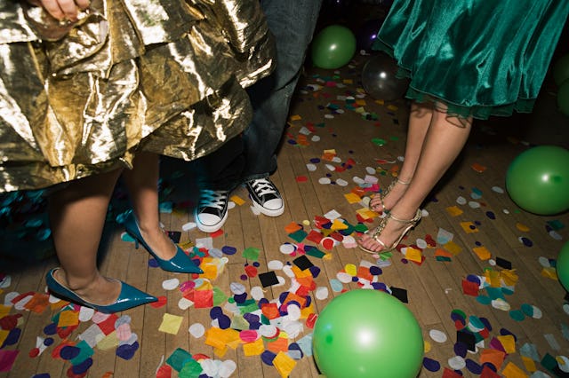 Two girls wearing dresses beside a boy in converse at a party with balloons on the floor around them...