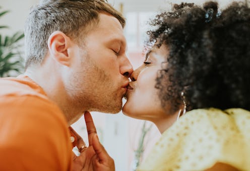 Close-up, low angle view of a young, beautiful, interracial heterosexual couple tenderly kissing. Th...