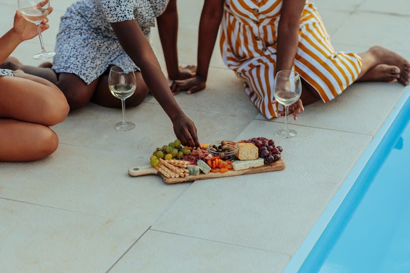 Close up of woman eating food at gathering with her friends near pool