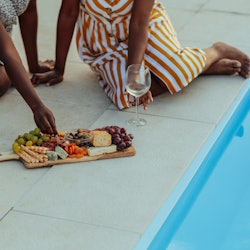 Close up of woman eating food at gathering with her friends near pool