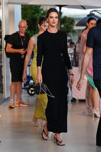 Alessandra Ambrosio wearing a long black dress with strappy black leather sandals