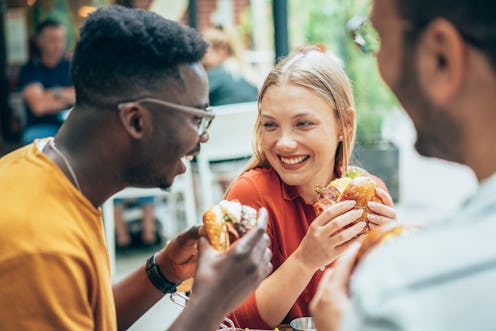 Friends eating burgers and have fun in outdoor restaurant