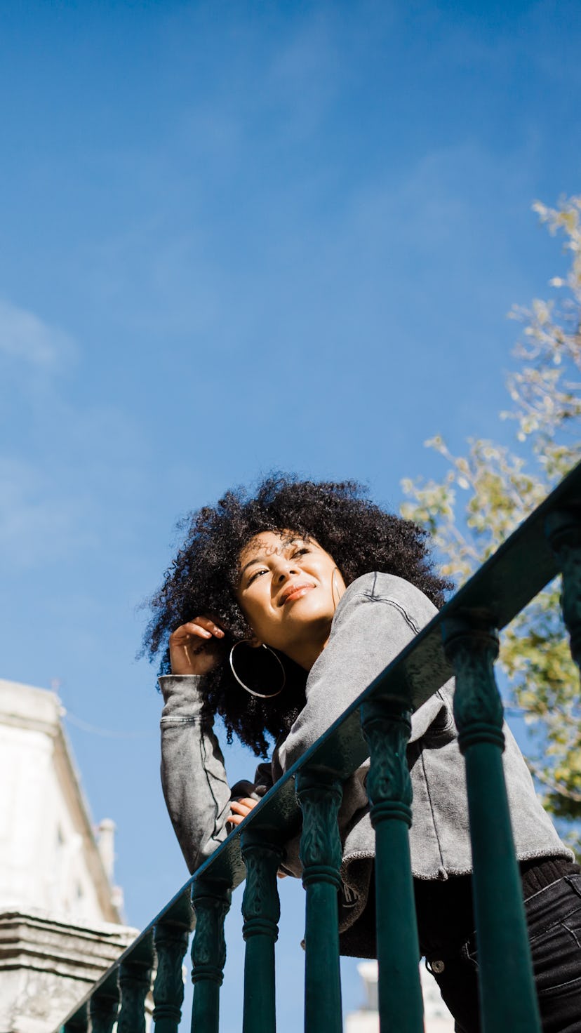 A woman leans on a balcony. The Luckiest Zodiac Signs In June 2022