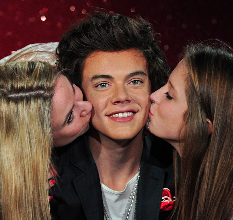 Fans kiss a waxwork model of Harry Styles, a member of English-Irish boy band One Direction, during ...