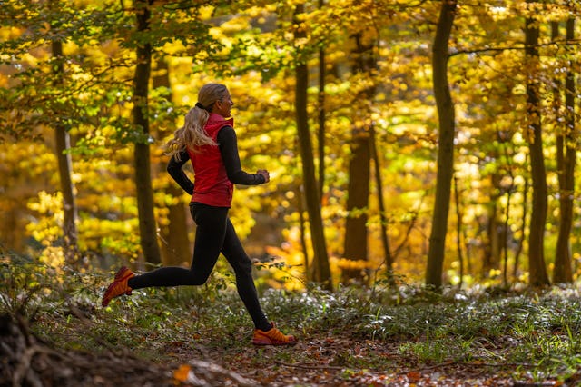 side view of happy sporty mature 46 years old woman, female athlete with long hair jogging running a...