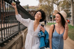 Happy romantic couple of female tourists walking the streets of Barcelona together. Cancer and leo c...