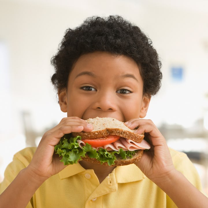 A happy boy eating a sandwich