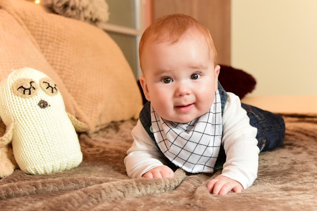 Red haired baby boy lying on his stomach looking at the camera with a Roman baby name 