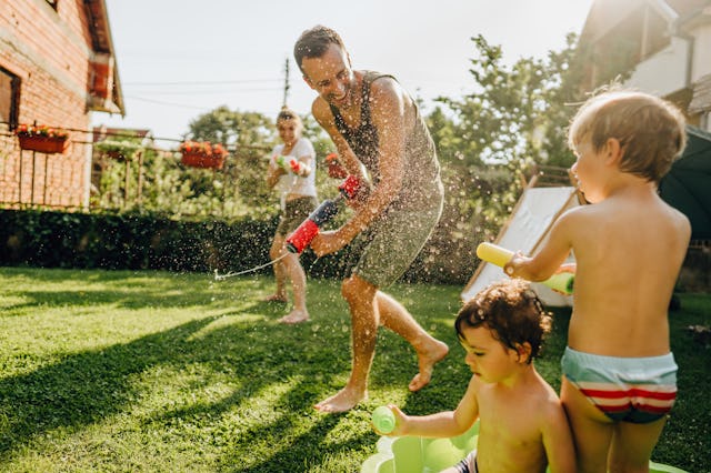 Photo of a happy family enjoying in a water battle in their yard