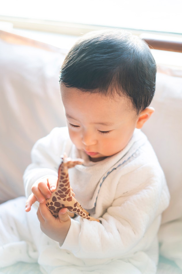 Baby with a Roman baby boy name holding a giraffe model