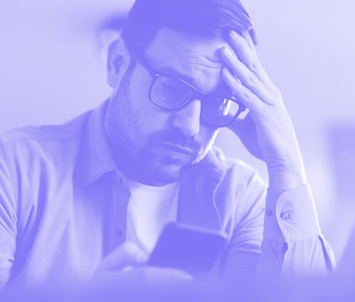 Worried man reading a problematic text message on cell phone at home.