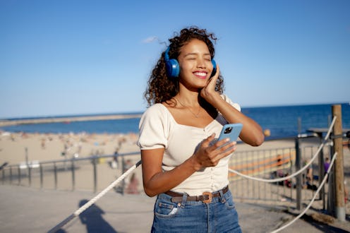 Portrait of a teenage girl in front of the beach listening to podcasts about juneteenth's history.