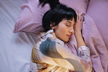 Above shot of a young Caucasian woman lying in her bed, sleeping.