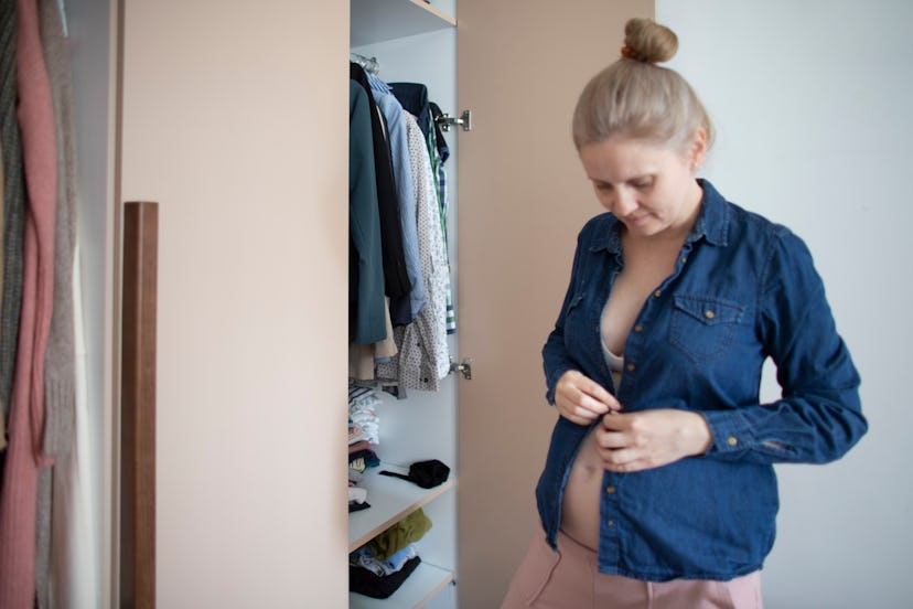 Young, pregnant woman organizing her clothes.